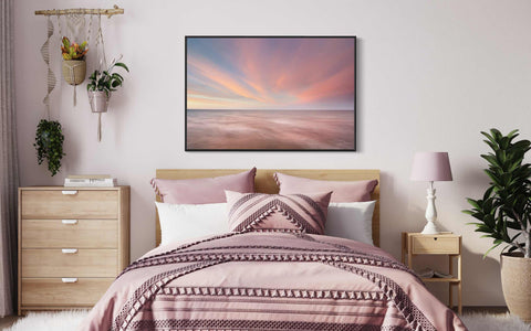 a bed room with a neatly made bed and a painting on the wall