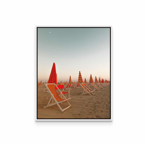 a row of lawn chairs sitting on top of a sandy beach